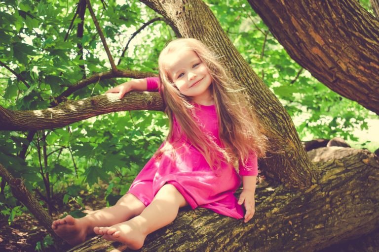 Niña sonriendo encima de un arbol